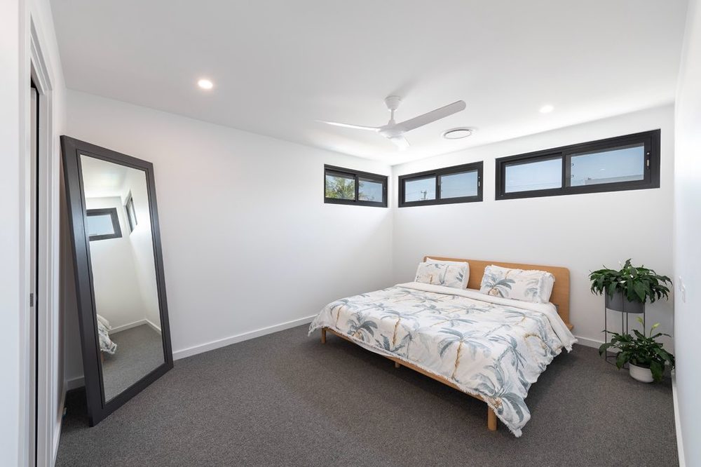 Bright bedroom with full-length mirror and timber flooring
