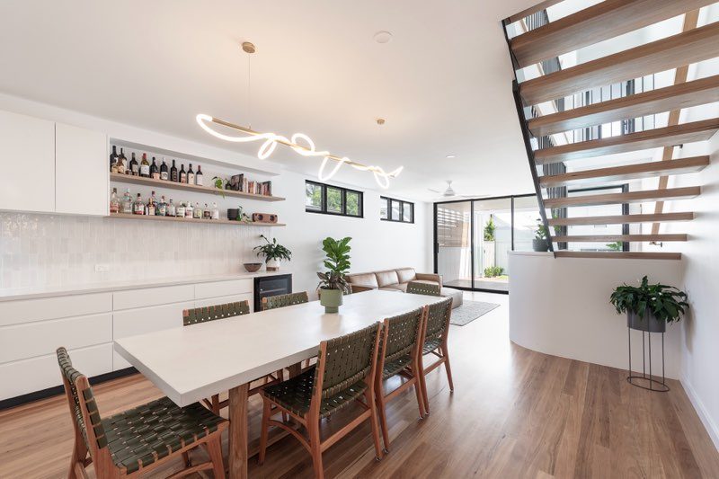 Dining area with timber floors, designer pendant light and built-in shelving