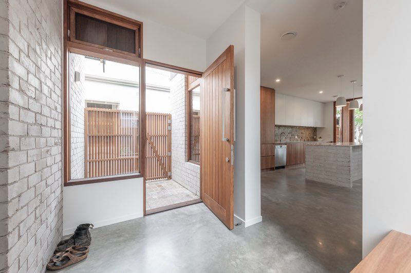 Entry foyer with timber pivot door and white-painted brick wall