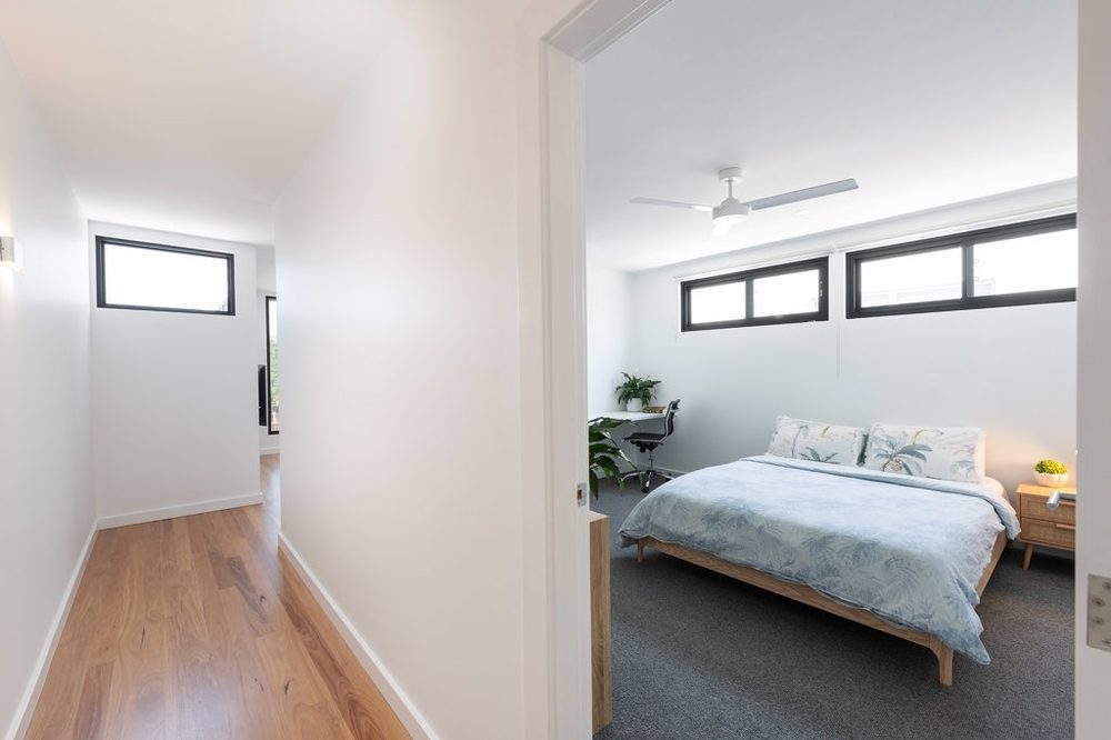 Bedroom and hallway with timber floors and crisp white walls