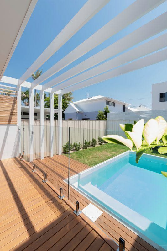 Outdoor pool area with white-painted pergola and timber decking