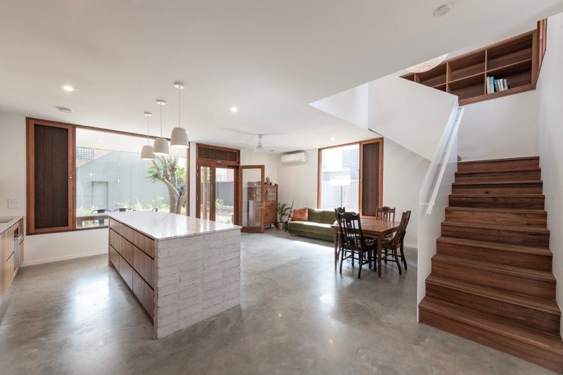 Open-plan living and dining area with white walls and timber staircase